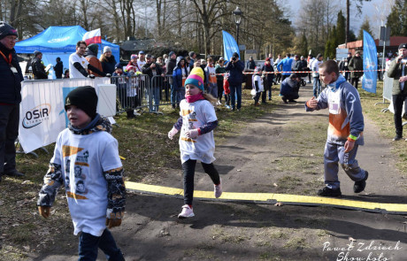 Na zdjęciu widoczni wychowankowie Mos Stargard pomagający w obsłudze biura zawodów i wydawania pakietów startowych, wyznaczania i taśmowania trasy, przewozu, rozładunku i załadunku sprzętu oraz w pracach porządkowych oraz biorący udział w biegu pod nazwą Tropem Wilczym